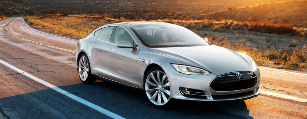Expert Tesla Maintenance & Repair in Fremont, CA at Driven Auto Care. Image of Silver Tesla sedan driving on open road with mountains in the background.