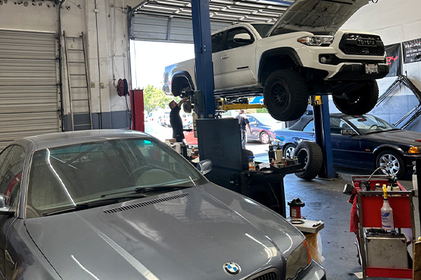 Premier dealership alternative for auto repair near me in Fremont, CA with Driven Auto Care. Image of gray BMW sedan and White Toyota Tacoma in shop bay for auto repair and maintenance services.