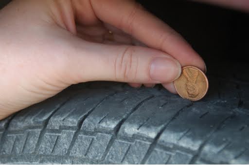 Fall Tire Care for Your Honda CR-V: Ensuring Safety on Slick Roads in Campbell, CA, with Driven Auto Care. A hand holding a penny over a tire gap.